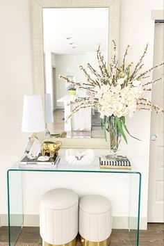 a white and gold console table with two stools