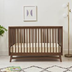 a baby crib in the corner of a room next to a lamp and potted plant