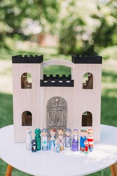 a small wooden toy castle on top of a white table with other toys around it