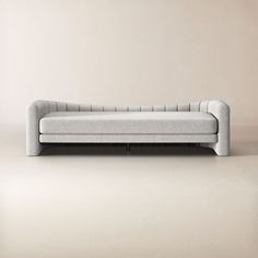 a gray couch sitting on top of a white floor next to a beige wall in an empty room