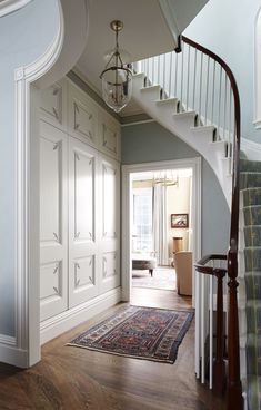 an entry way leading to a foyer with white painted walls and wooden floors, along with a chandelier hanging from the ceiling