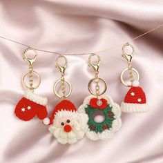 three crocheted christmas ornaments hanging from a line on a white satin background,