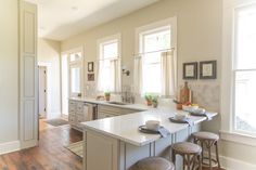 a large kitchen with an island and two stools in front of the counter top