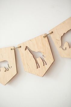 three wooden animals are hanging on the wall next to each other, and one is cut out from wood