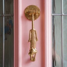 a pink door with a gold handle and a fish figure on it's side