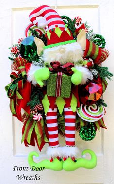 a christmas wreath hanging on the front door with santa's helper and candy canes