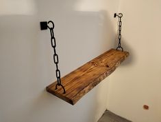 a wooden shelf with chains hanging from it's sides on the wall next to a door