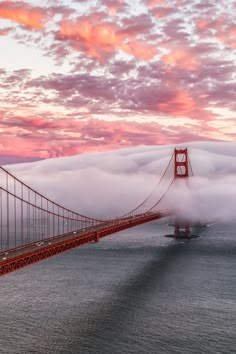 the golden gate bridge in san francisco, california is shrouded with clouds as the sun sets