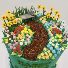 a green cake with flowers and gardening tools on it