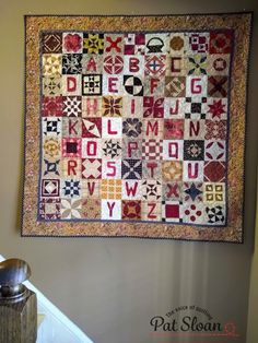 a quilt hanging on the wall next to a stair case with letters and numbers in it