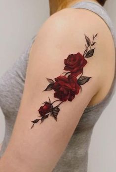 a woman's arm with red roses on it and leaves coming out of the back