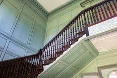 an ornate staircase in a building with green walls and wood paneling on the sides