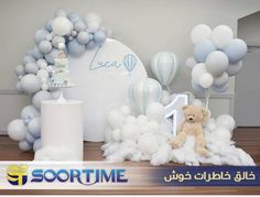 there is a teddy bear and balloons on the table with it's name written in arabic