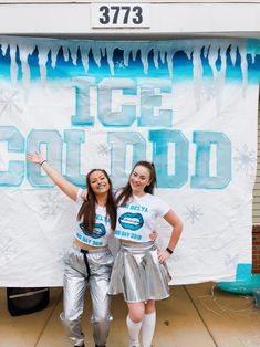 two girls standing in front of a ice cold sign