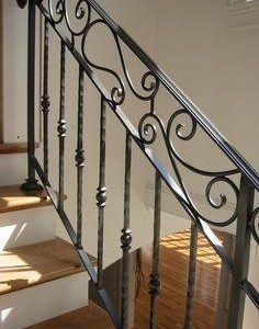 an iron stair rail with wood floors and white walls