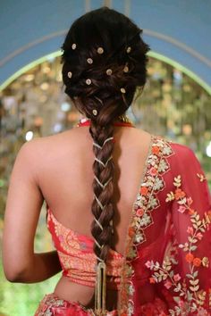 the back of a woman's head with braids in her hair and wearing a red sari