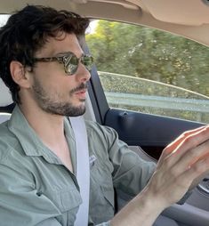 a man sitting in the driver's seat of a car while holding an object