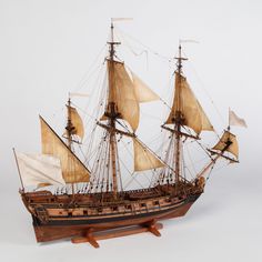 a wooden model ship with white sails