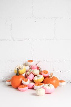 a pile of fake pumpkins sitting next to a white brick wall