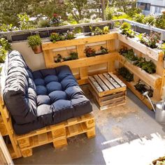 a couch made out of wooden pallets on top of a roof with potted plants