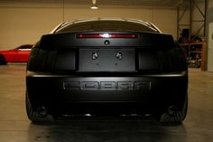 the rear end of a black sports car in a garage