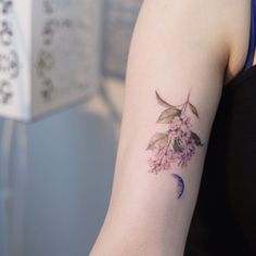 a woman's arm with flowers and a half moon tattoo on her left arm