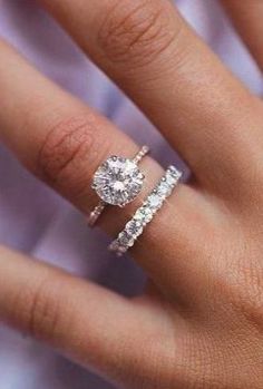 a woman's hand with two engagement rings on her left and the middle finger