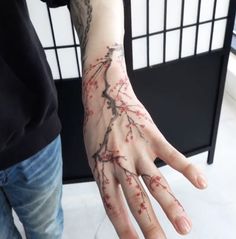 a person's hand with tattoos on it and flowers painted on the palm,