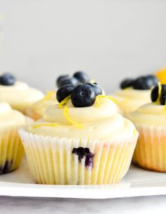 blueberry cupcakes on a white plate with lemon zest and blueberries