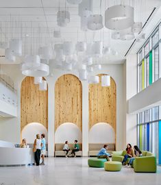 people are sitting in the lobby of an office building with high ceilings and large windows