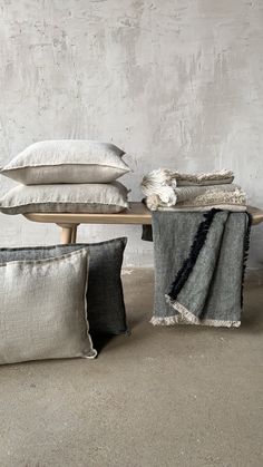 pillows and blankets on a table in front of a concrete wall