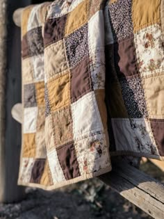 a patchwork quilt hanging on the back of a wooden bench