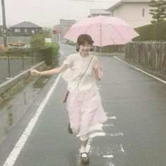 a woman is walking down the street with an umbrella in her hand and she is smiling