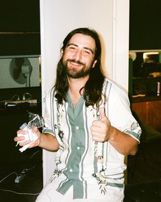 a man with long hair and beard holding a wii remote in his hand while sitting on a chair