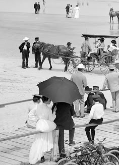 several people standing on a boardwalk with horses and buggies