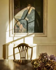 a wooden table sitting under a painting next to a vase with flowers on top of it