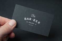 a hand holding a business card that says the barber shop