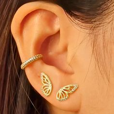 a close up of a person's ear with two gold butterflies on it and one is