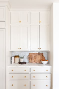 a kitchen with white cabinets and gold handles