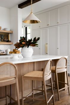 an image of a kitchen setting with white countertops and wooden chairs in the center