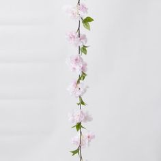 pink flowers are hanging from the side of a white wall