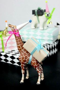 a giraffe figurine holding a gift box and wearing a party hat