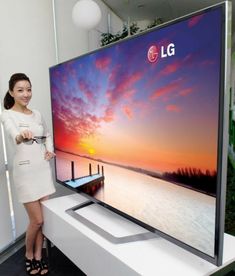 a woman standing next to a large screen tv