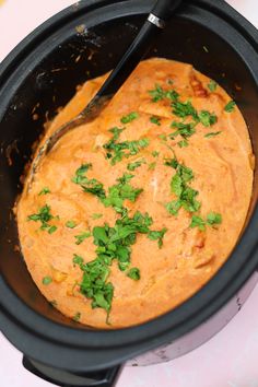 a black crock pot filled with food and garnished with parsley