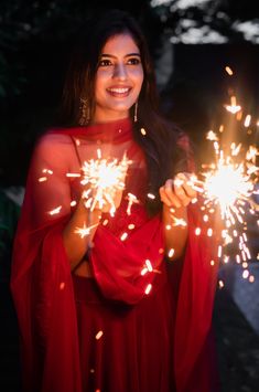 a woman in a red dress holding sparklers