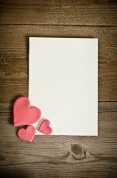 two hearts are placed next to an empty paper