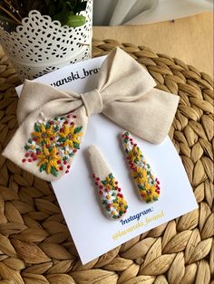 a pair of earrings on top of a card next to a potted plant in a wicker basket