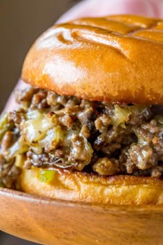 a close up of a hamburger on a wooden plate with text that reads phily cheese steak sloppy joes