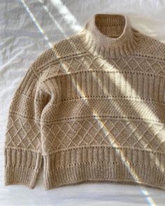 a sweater is laying on a bed with the sun shining through it's shadow