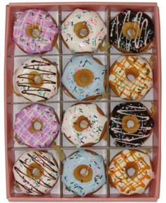 twelve glazed donuts with sprinkles in a pink box